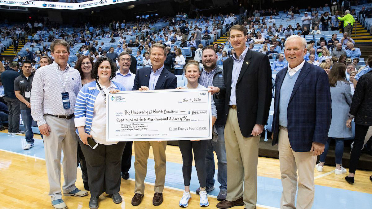 Chancellor Kevin Guskiewicz standing with a group from Duke Energy Foundation and holding a donation check. 