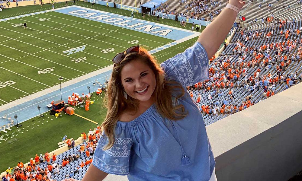 Michaela Barnette stand with her arms open at a UNC football game
